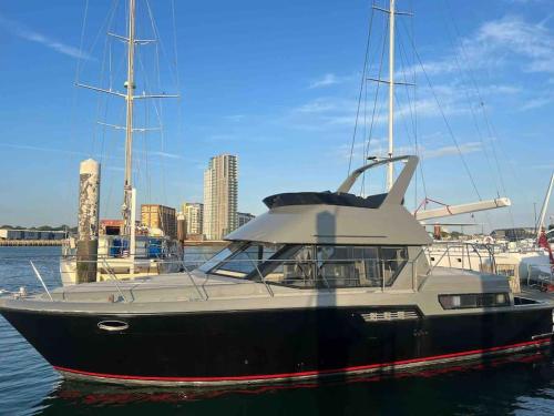 南安普敦YACHT "X" - 44 FOOT MODERN YACHT ON 5 STAR OCEAN VILLAGE MARINA - minutes away from city centre and cruise terminals, Free parking ,SPA package available!的黑白的船坐在水里