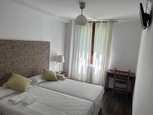 La Fortunadabadain的一间卧室设有两张床、一张桌子和一个窗口。