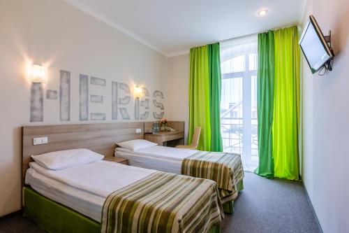 基辅PracticOtel的配有绿窗帘的酒店客房的两张床