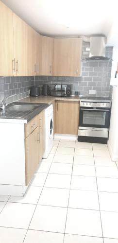 KentGravesend 1 Bedroom Flat 2 Min Walk to Station & Town Centre - longer stays available的厨房配有木制橱柜和白色瓷砖地板。