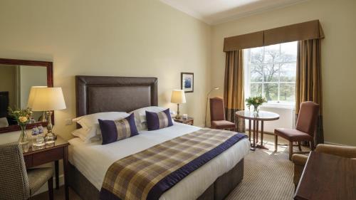 隆霍斯雷Macdonald Linden Hall Hotel, Golf & Spa的配有一张床、一张书桌和一扇窗户的酒店客房