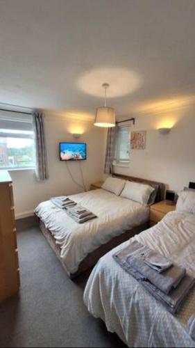 卢顿4 Bedroom 4 En Suite House Close to A5 & Whipsnade的一间卧室配有两张床和一台平面电视