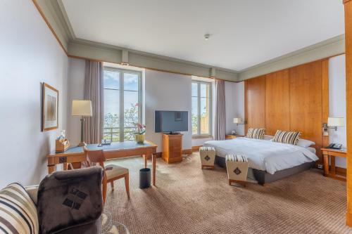 纳沙泰尔美岸酒店的一间卧室配有一张床、一张书桌和一台电视。