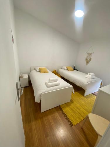 塞洛里库迪巴什图S&C HOSTING的配有白色墙壁和木地板的客房内的两张床