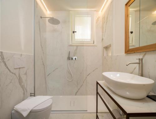 努马纳Borgopetra Resort的白色的浴室设有水槽和淋浴。