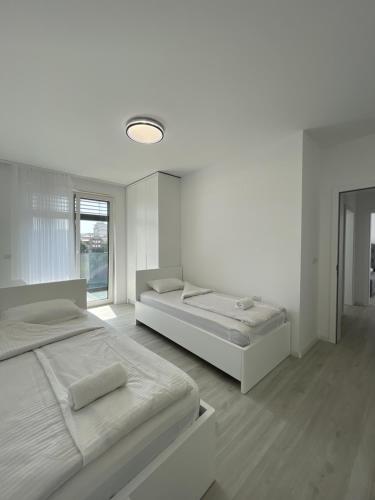 GjakoveGega Apartments的一间白色卧室,配有两张床和窗户