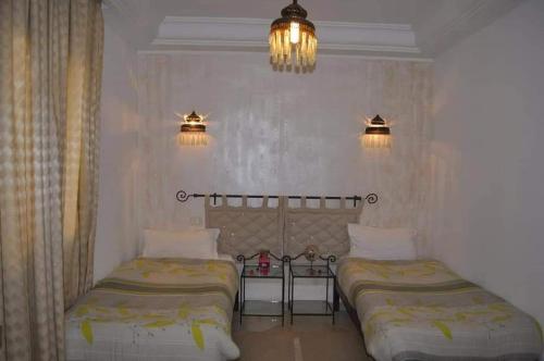 迈来亚Résidence Chahd de Charme的一间卧室配有两张床、两个灯和一个吊灯。