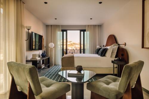 加亚新城The Rebello Hotel & Spa - Small Luxury Hotels Of The World的酒店客房带一张床、一张桌子和椅子