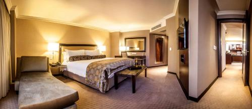 比勒陀利亚南孙比勒陀利亚酒店的酒店客房带一张大床和一把椅子
