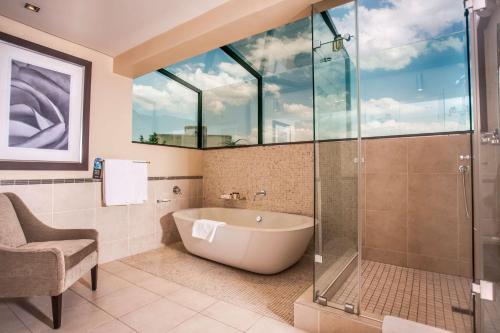比勒陀利亚南孙比勒陀利亚酒店的带浴缸和玻璃淋浴间的浴室。