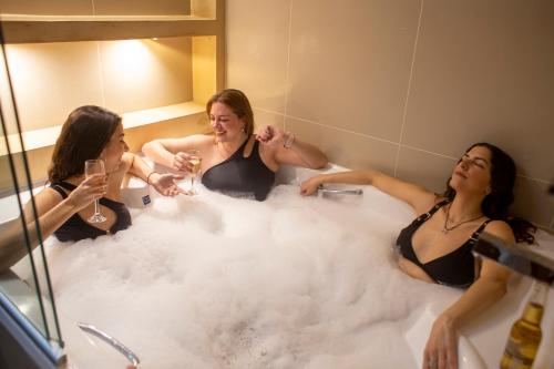 特尔马斯德里奥翁多Hotel Cálido Termal的三个妇女在浴缸里装满泡沫