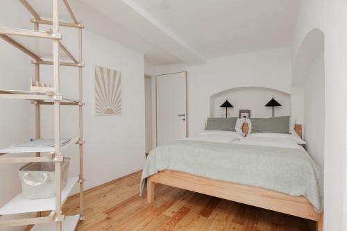 因斯布鲁克Das Grüne Haus - Boutique Apartments ecofriendly的一间铺有木地板的白色卧室,配有一张床
