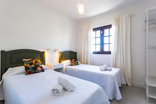 蒂亚斯Villa Tara的客房设有2张带白色床单的床和窗户。