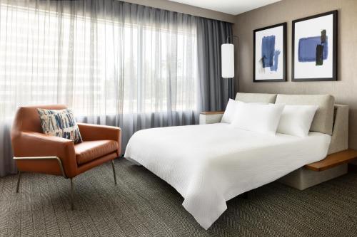伍德兰希尔斯洛杉矶伍德兰希尔斯万怡酒店的酒店客房带一张大床和一把椅子