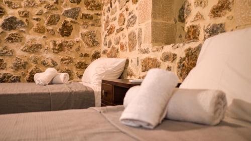 NíthavrisMitato Eagle's Nest Peristeres的一间卧室设有两张床和石墙