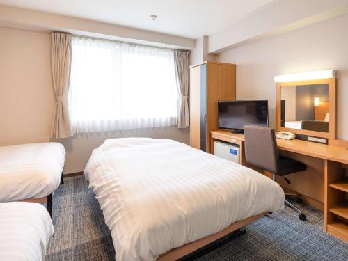 彦根市彦根市康福特茵酒店的酒店客房设有两张床、一张桌子和一台电视。