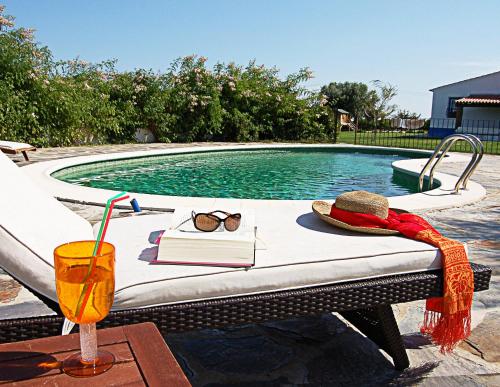 蒙萨拉什橘园山旅馆的一张桌子,旁边是游泳池,旁边是一本书和一杯饮料