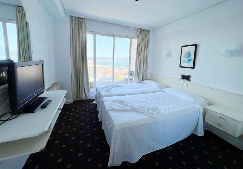 拉雷多Hotel Miramar Laredo的酒店客房设有两张床和一台平面电视。