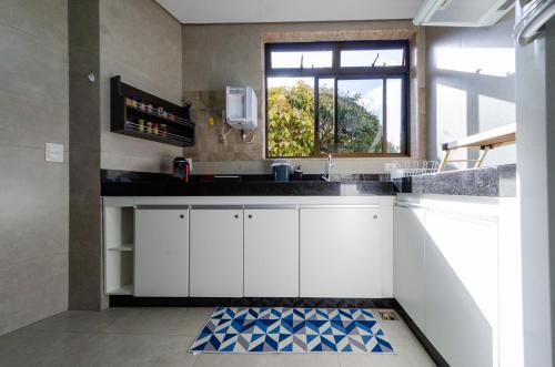 贝洛奥里藏特apartamentos Coração Eucarístico的厨房配有白色橱柜和窗户。