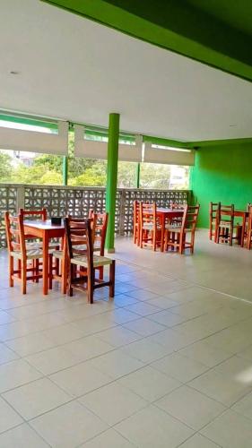 希利特拉Hotel posada onix xilitla的餐厅设有木桌和椅子,拥有绿色的墙壁
