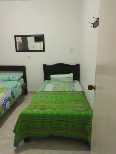 波帕扬HOTEL CASA BLANCA的一间卧室配有一张带绿色棉被的床
