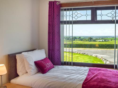 卡姆诺克Lowesmuir Cottage的一间卧室配有一张床和一个带紫色窗帘的窗户