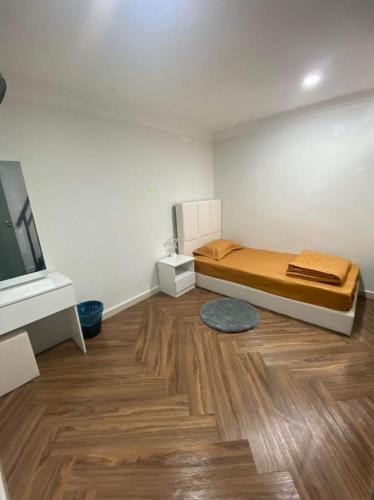 关丹Amani Homestay的一间卧室配有一张床和一台电视,铺有木地板