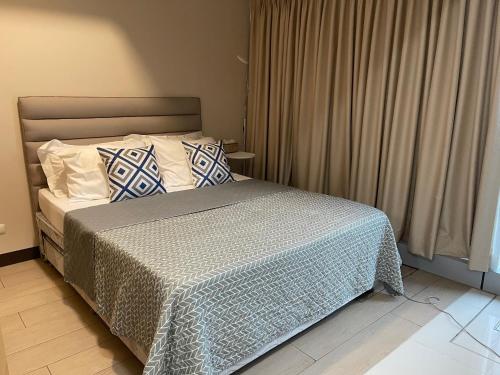 马尼拉1 BR condo Uptown Parksuites BGC, high floor, morning sun的一间卧室配有一张带蓝色和白色枕头的床