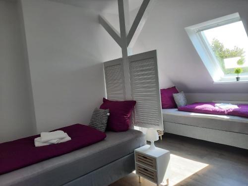 桑德Villa Mariensiel II的客房配有两张带紫色枕头的床和窗户。