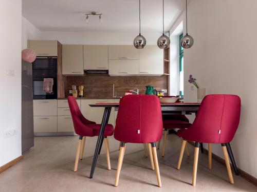 托尔明Hiša Magnolija的厨房配有桌子和四把红色椅子