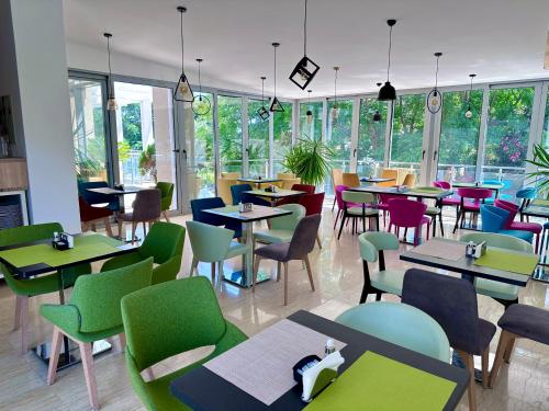 苏托莫雷Hotel Porto Sole的餐厅设有多彩的桌椅和窗户。