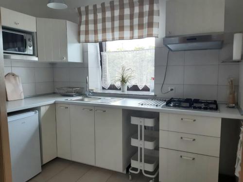 苏莱吉Apartamenty Rodzinne Pilica PARK的厨房配有白色橱柜、水槽和窗户。