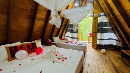 哈伯勒内Habarana Tree House Ambasewana Resort的卧室配有两张床,地板上设有气球。