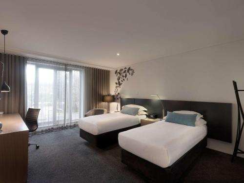 墨尔本The Como Melbourne的酒店客房配有两张床和一张书桌