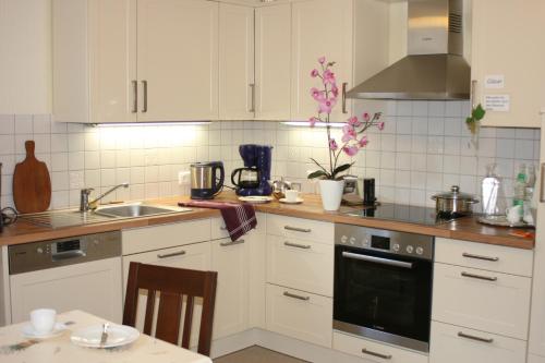 科赫姆Gästehaus Aladin的厨房配有白色橱柜、水槽和桌子