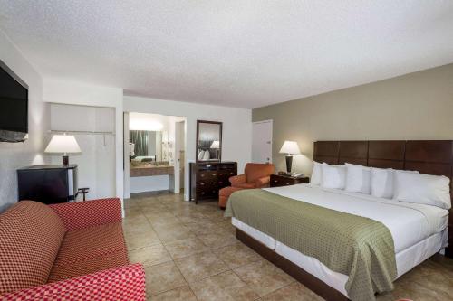 圣彼得堡Days Inn by Wyndham St. Petersburg / Tampa Bay Area的酒店客房带一张大床和一把椅子