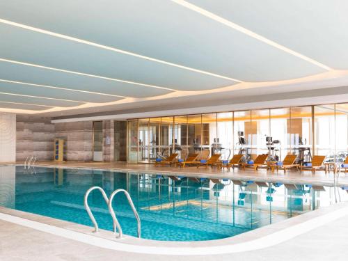 常熟常熟理文铂尔曼酒店 的大楼内带椅子的游泳池