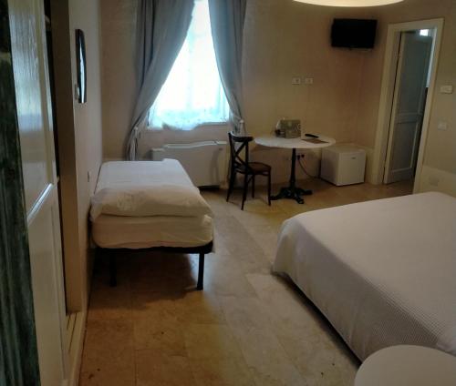 蒙德拉戈内Hotel & Resort Lunatenuta的客房设有两张床、一张桌子和一扇窗户。