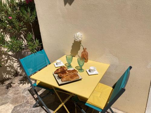 尼姆Le studio D'auguste- Cœur de Nîmes-chaleureux-emplacement idéal的一张带椅子的黄色桌子和一盘食物