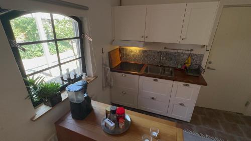 赫尔湾Stort rymligt boende med två sovrum och pentry i lantlig miljö的厨房配有白色橱柜和带窗户的柜台。