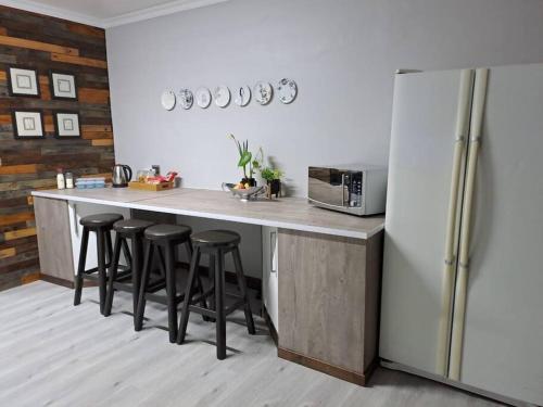 布隆方丹Mossie Nes - Self Catering的厨房配有带凳子的柜台和冰箱。