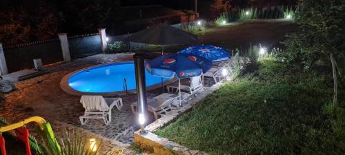 桑丹斯基Sunshine villa Dzhigurovo的游泳池旁的游泳池配有两把遮阳伞和椅子