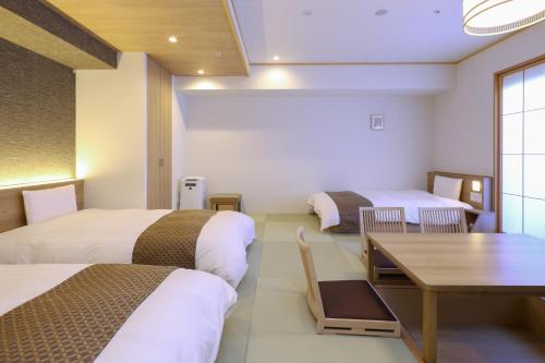 东京Dormy Inn Premium Ginza的酒店客房设有两张床和一张桌子。