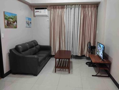 马尼拉Spacious 1 bedroom unit in Araneta Center Cubao的客厅配有黑色真皮沙发和桌子