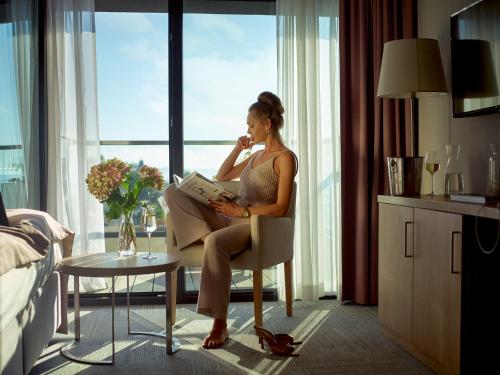 梅尔诺Baltivia Sea Resort的坐在椅子上读书的女人
