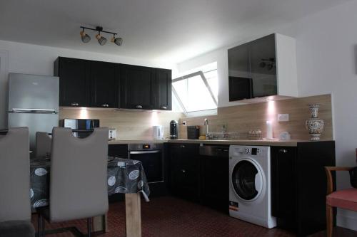 龙斯莱班Appartement entièrement rénové à Ronce Les Bains avec jardin的厨房配有黑色橱柜和洗衣机。