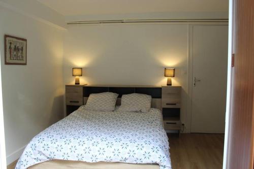 龙斯莱班Appartement entièrement rénové à Ronce Les Bains avec jardin的一间卧室配有一张带两盏灯的床。