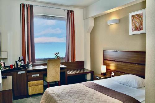 凯尔采泰科佐维梅林酒店的配有一张床、一张书桌和一扇窗户的酒店客房