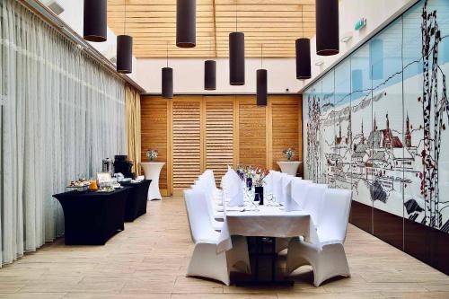 凯尔采泰科佐维梅林酒店的用餐室配有白色的桌子和白色的椅子
