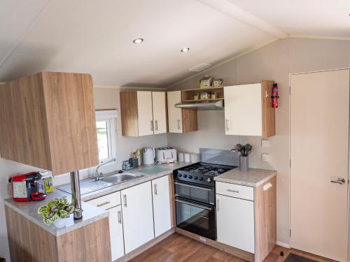 斯凯格内斯Caravan Skegness 8 Berth的厨房配有白色橱柜和炉灶烤箱。